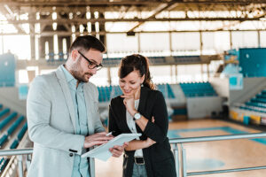 sports management - man and woman reviewing pad in basketball hall