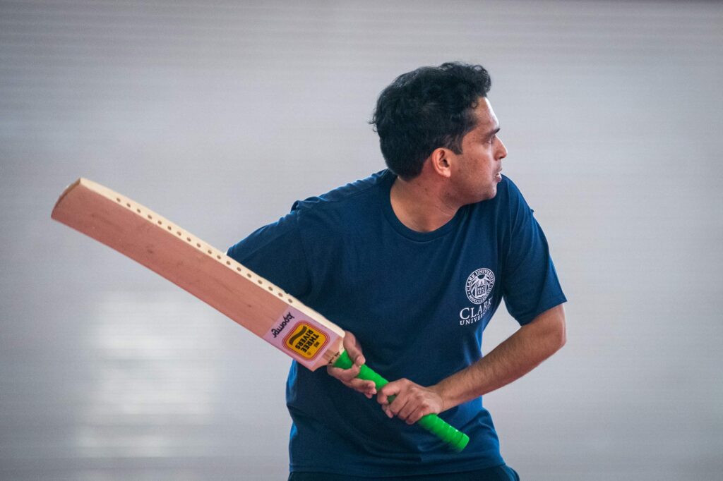 International student holding a cricket bat during a game on campus