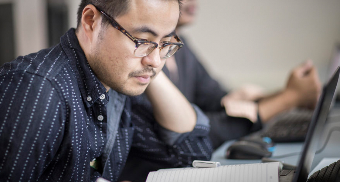 Student looking at notebook and laptop on table
