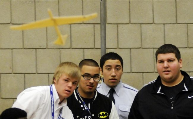 4 male young students flying paper plane