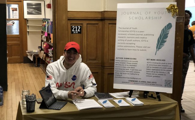 male youth sitting at desk in hall way