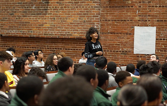 female student speaking out in front of class