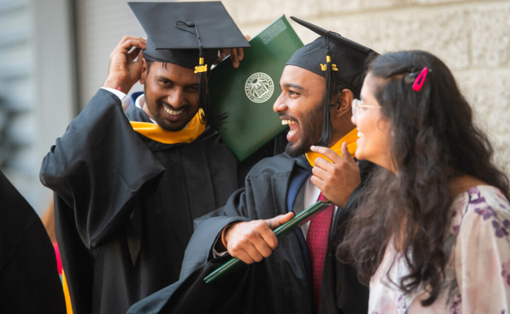 Graduate students smiling with diplomas