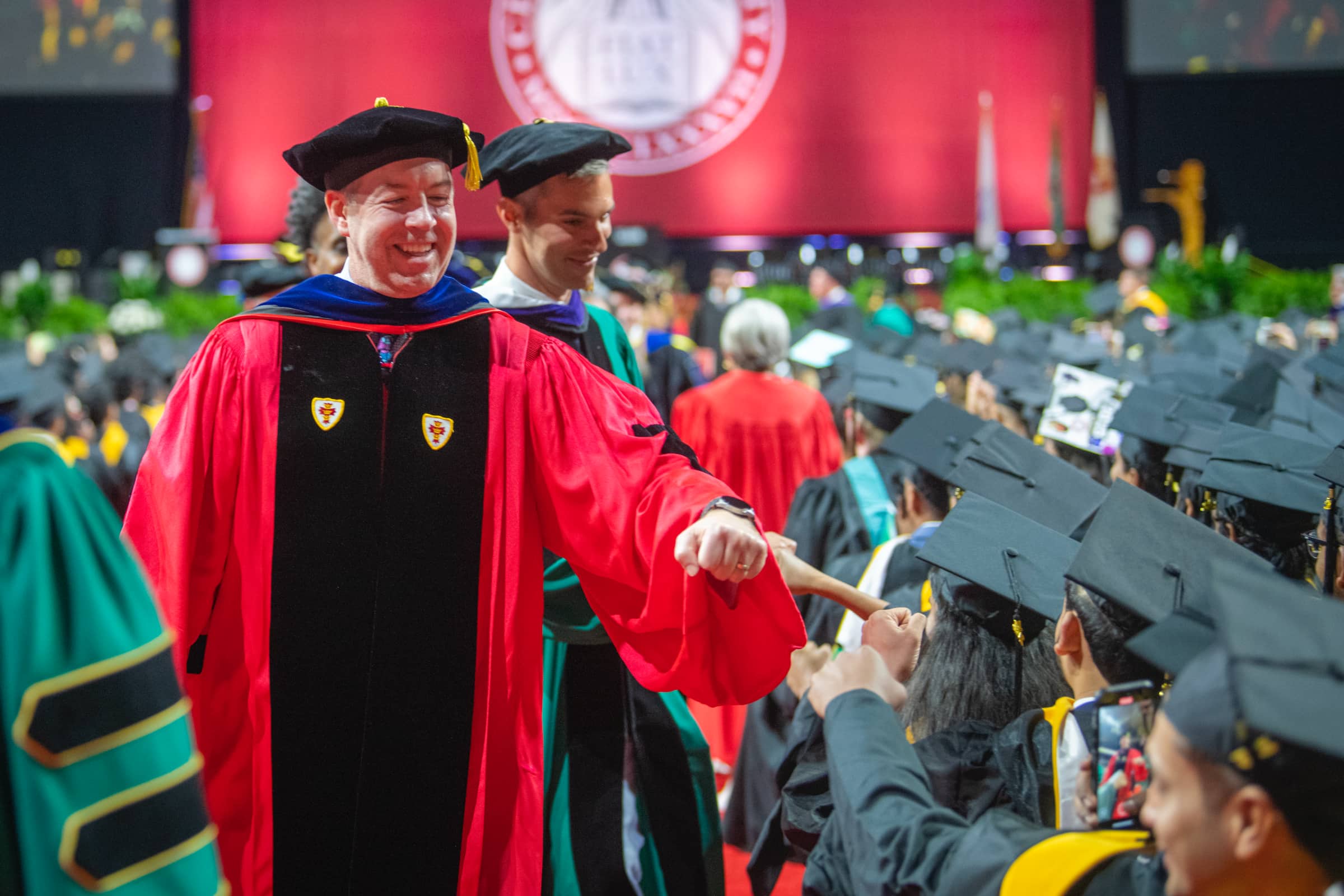 The provost fist bumps students down the aisle