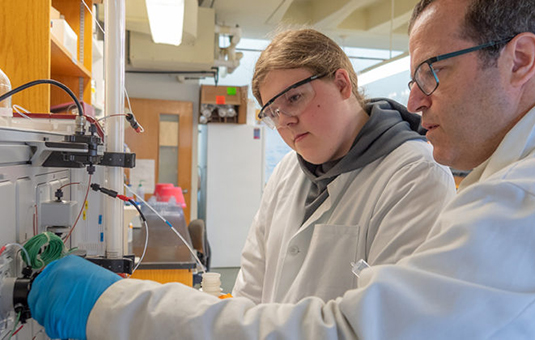 Ph.D. student working with younger student in lab