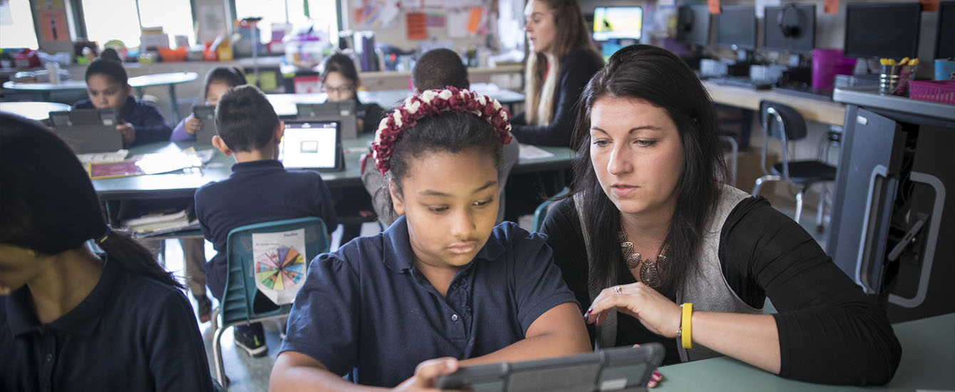 graduate student teaching younger child in classroom