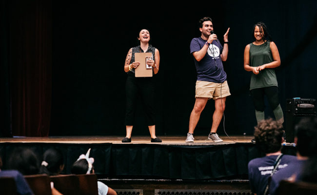 college students on stage putting on performance for young k-12 students