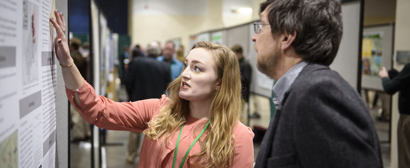 Student pointing to research poster