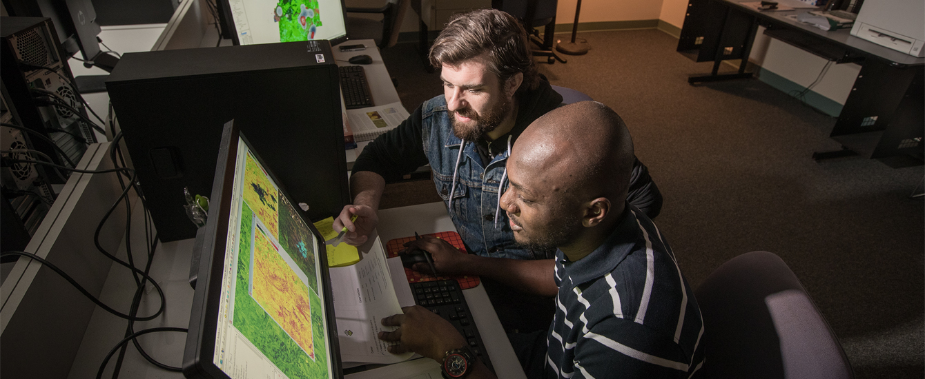 Two students examining map on a computer monitor
