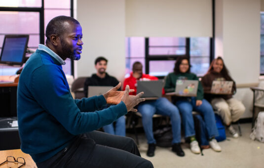 A Sustainability and Social Justice professor leads a group discussion in the classroom