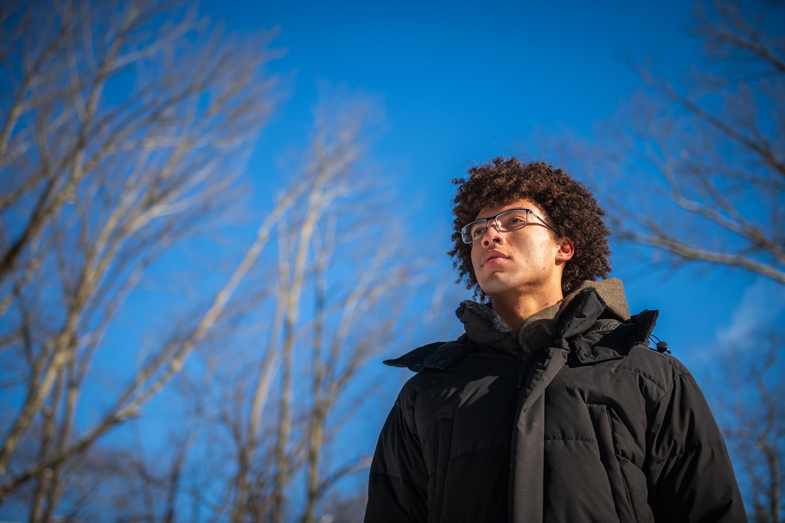 Aedan Derrick ’26 standing in the Hadwen Arboretum, Clark University, on a winter day.