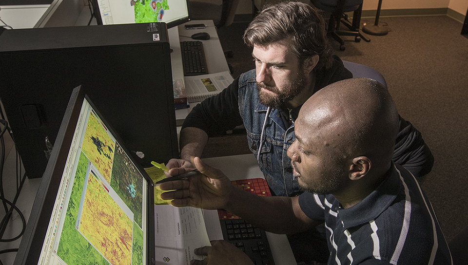 GIS students in classroom looking over maps