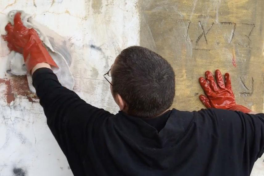 person wiping paint off wall
