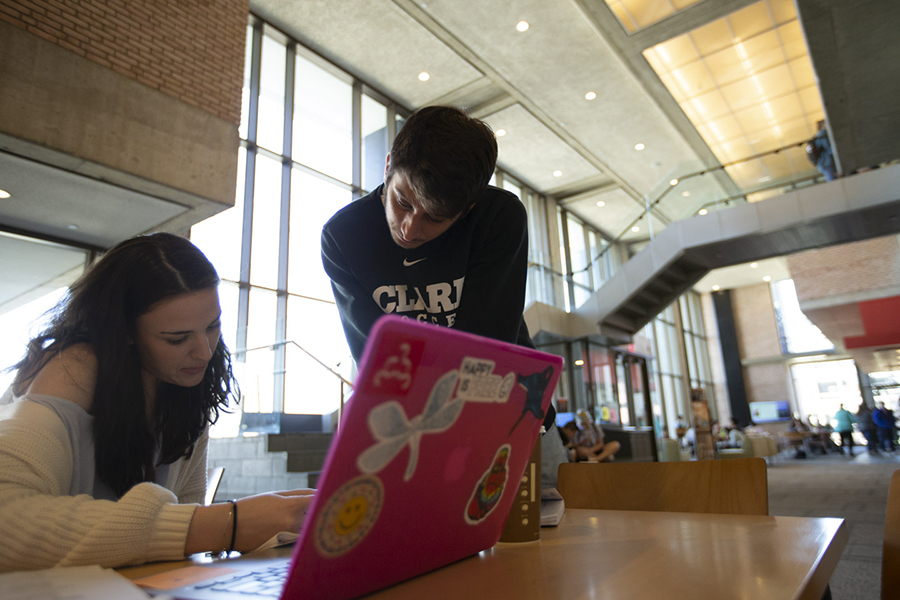 students looking over laptop in library