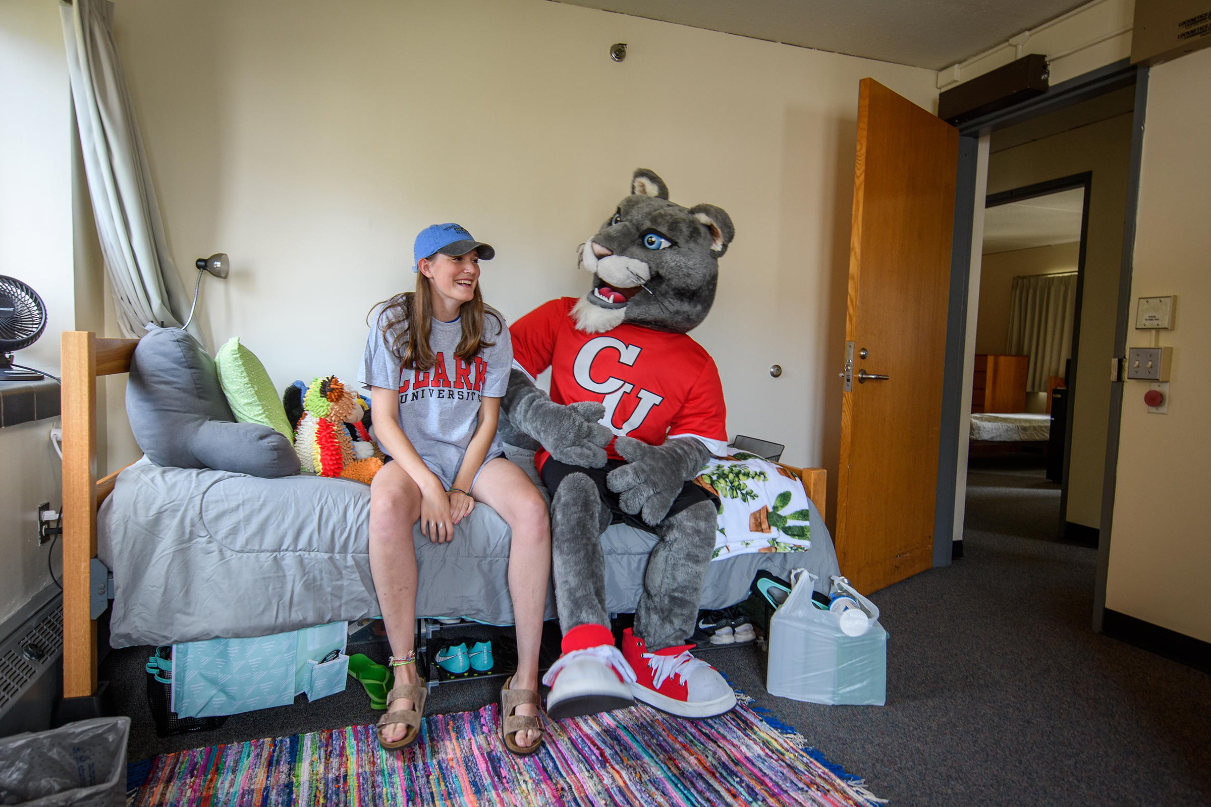 Hughes Hall - mascot sitting on bed with female student