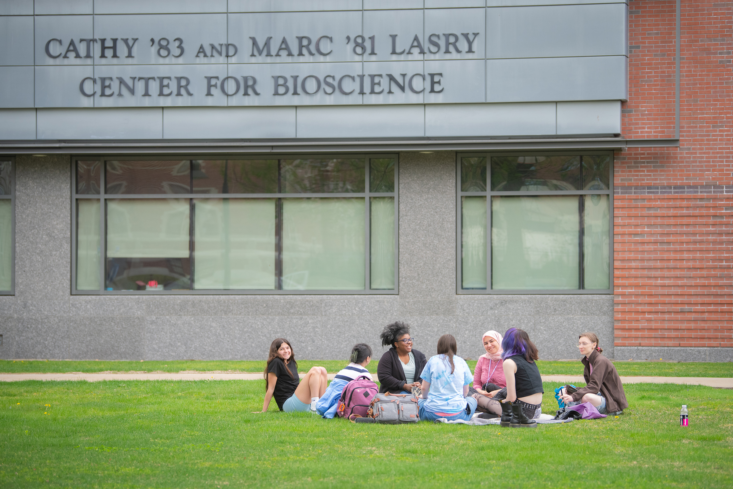 Lasry Center for BioScience - students sitting on grass in front of building