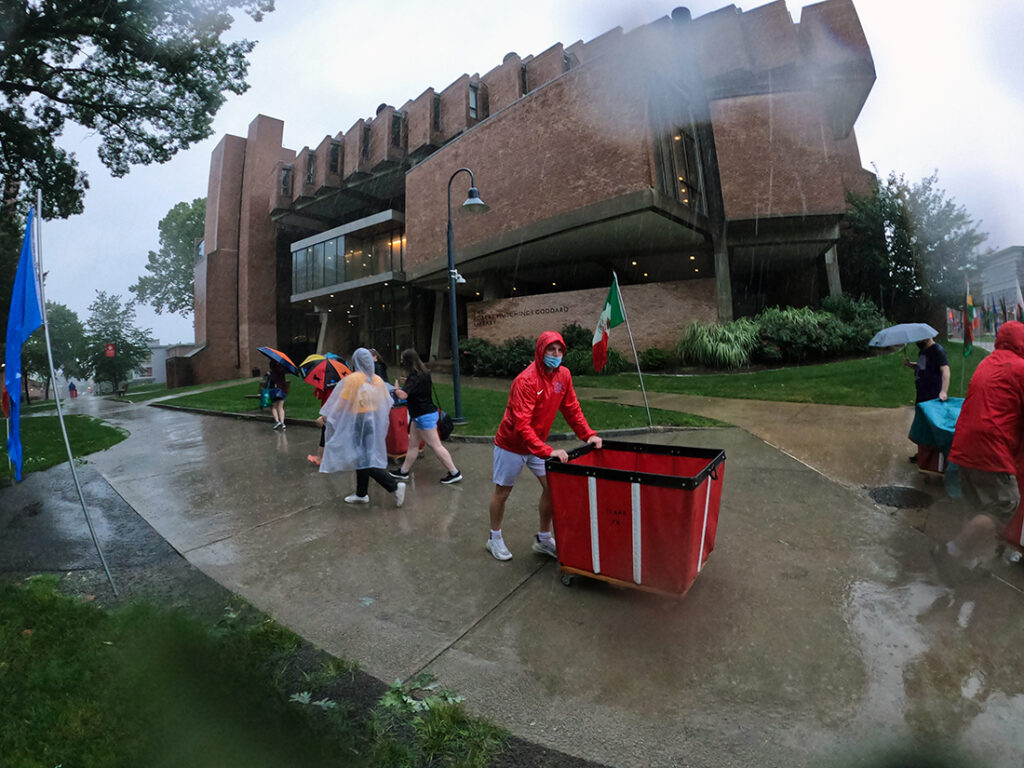 Clark University students on Move-In Day. One student pushes a moving bin.