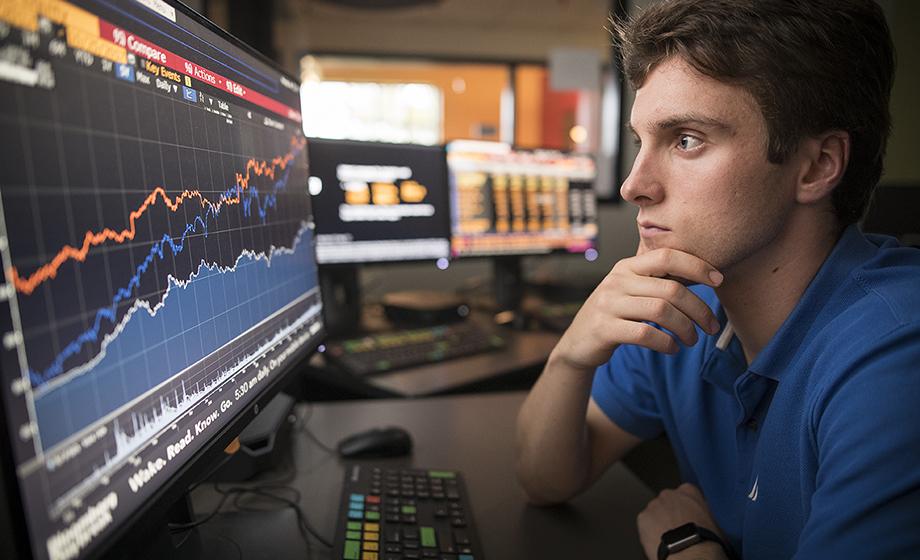 male student in front of computer screen with data analytics