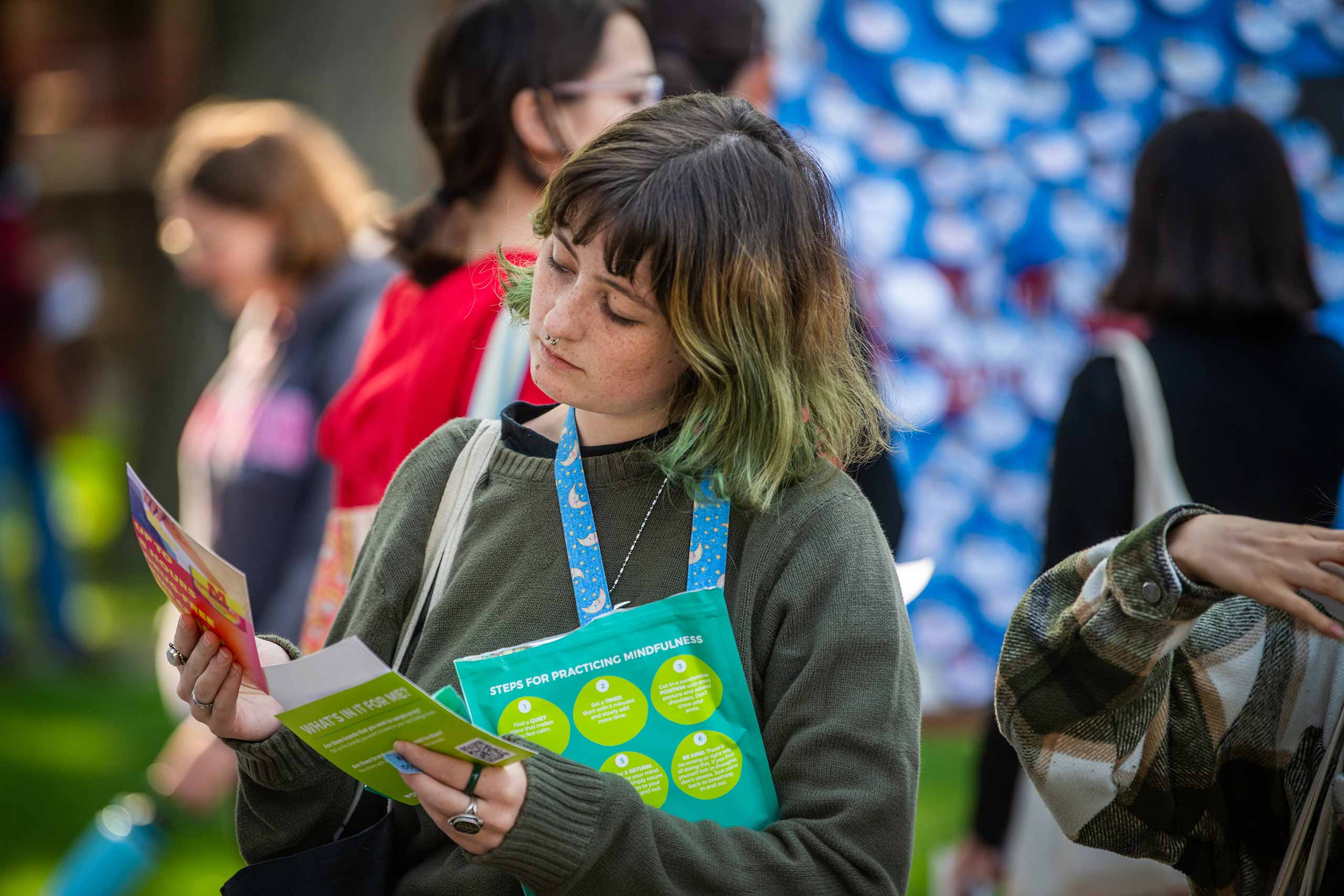 A student reviewing brochures about wellness and mindfulness during #FreshCheckDay, Clark University