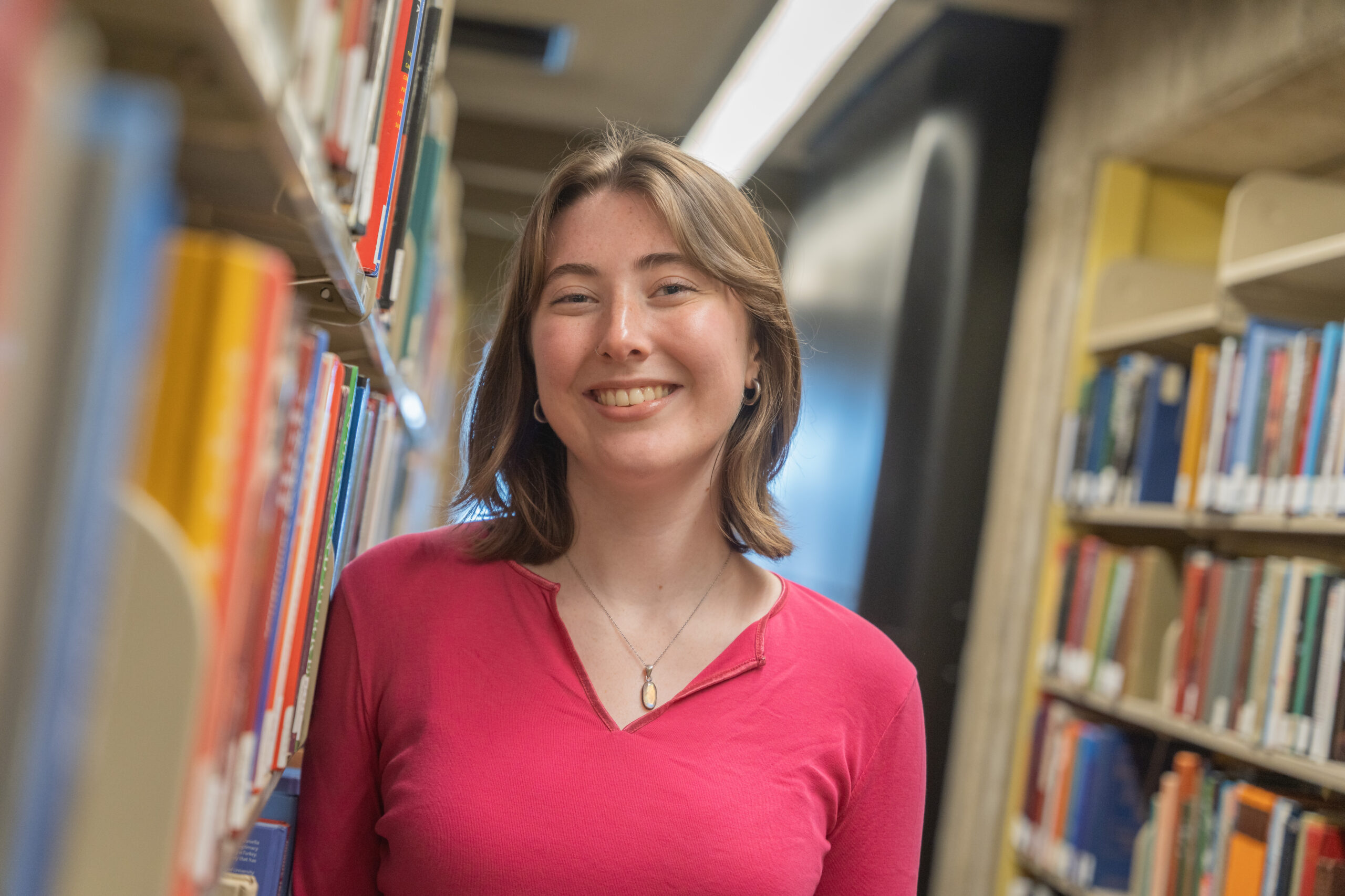 student poses for photo in library stacks