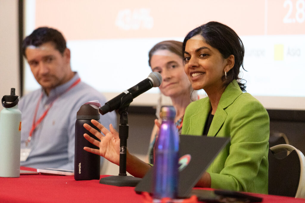 three people sit at table with microphones during panel