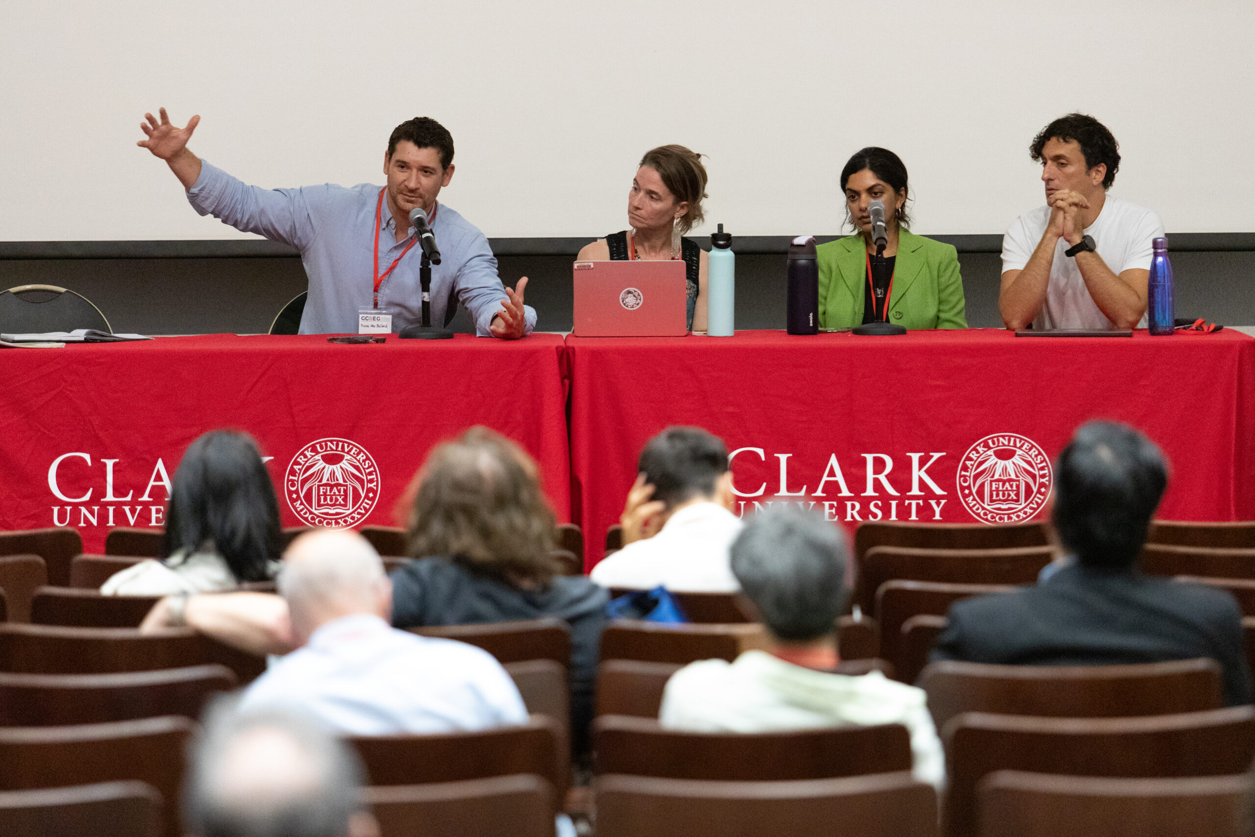 four people sit at table with microphones during panel