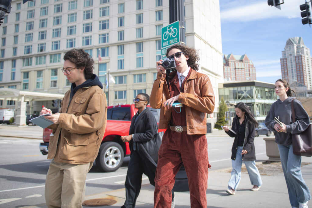 students and professor walk on city sidewalk