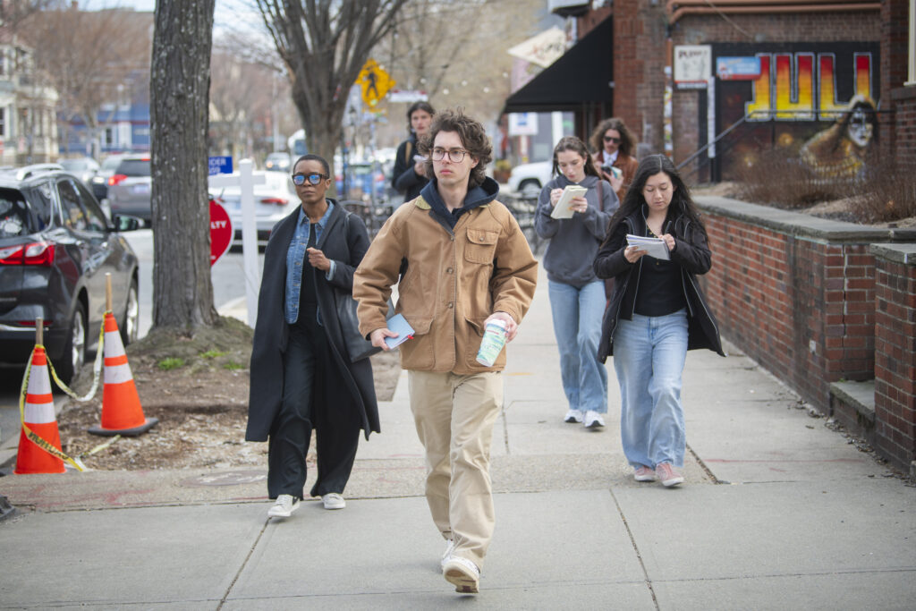 students and professor walk on city sidewalk