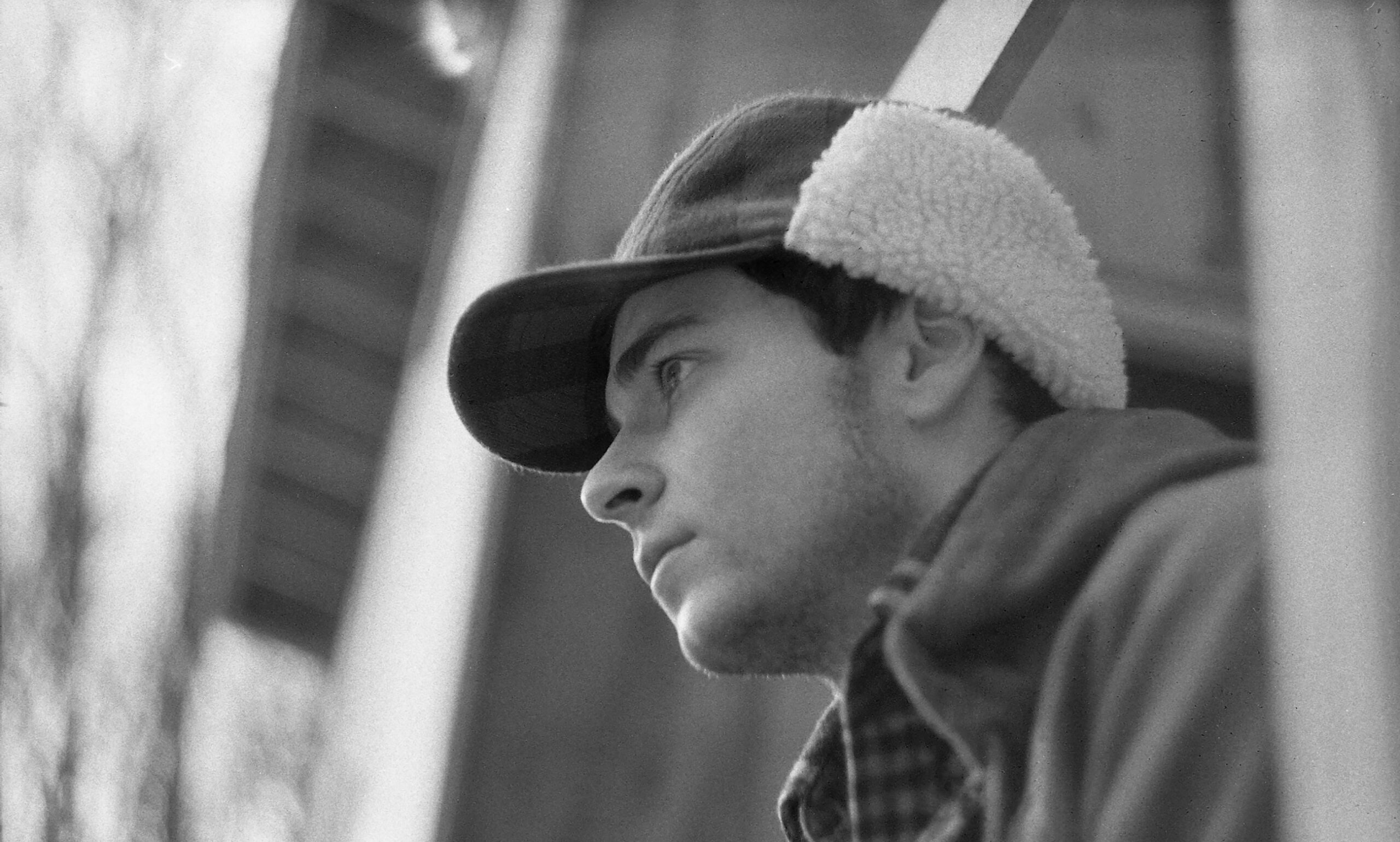 black and white photo of man in hat looking out window
