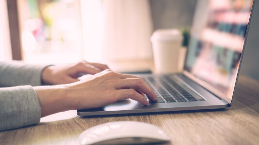 Hands typing on a laptop