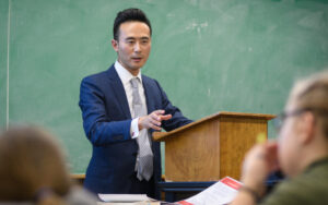 Professor Lex Lu in front of students at podium