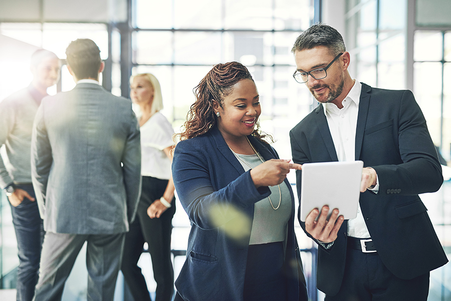 business administration - Shot of two coworkers talking together over a digital tablet in an office