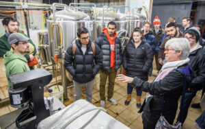 economics professor with students in beer distillery.