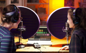 Multi Media students behind mics in recording studio doing a podcast