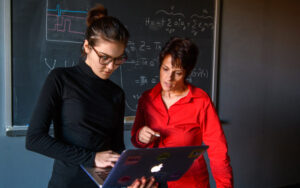 Physics professor with student looking over laptop