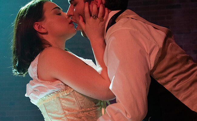 theatre arts students performing on stage - woman kissing man