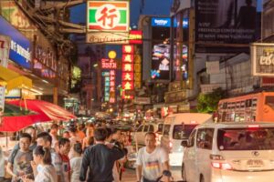 a bustling street filled with cars, pedestrians, and vendors