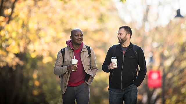 students in conversation as they walk across campus