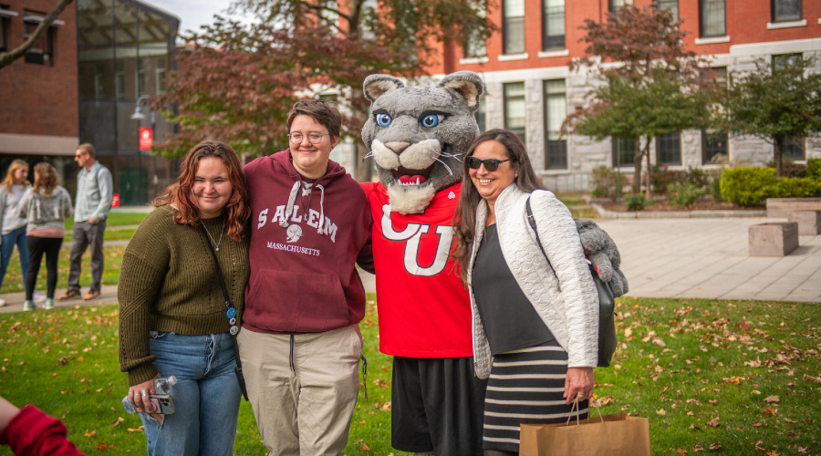 Student and family posing with Cougar mascot on campus green