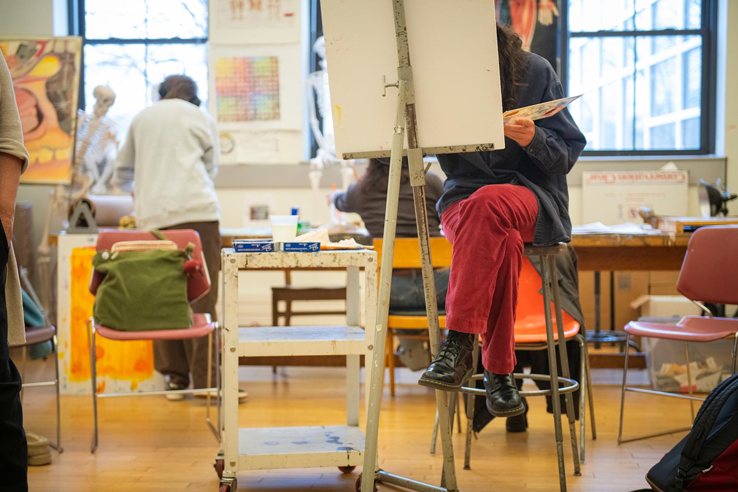 A student seated behind an easel in class at the Traina Center for the Arts, Clark University