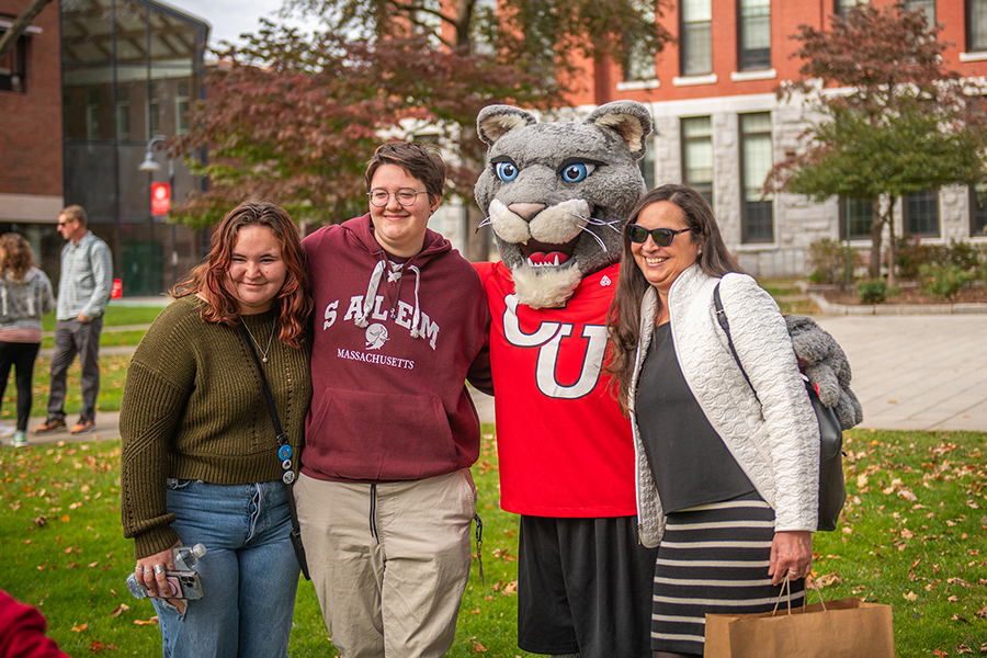 Student and family posing with Cougar mascot on campus green