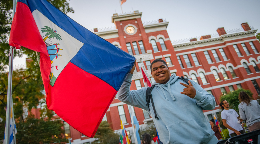 Student holding international flag in front of Jonas Clark Hall