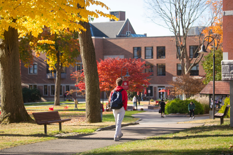 Student walking through campus with fall foliage