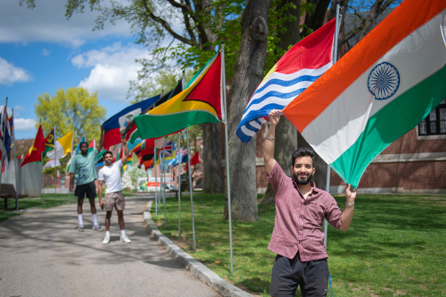Students holding international flags along Clark walk way