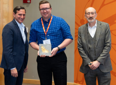 Don Spratt holding award, with two New England Biolabs scientists